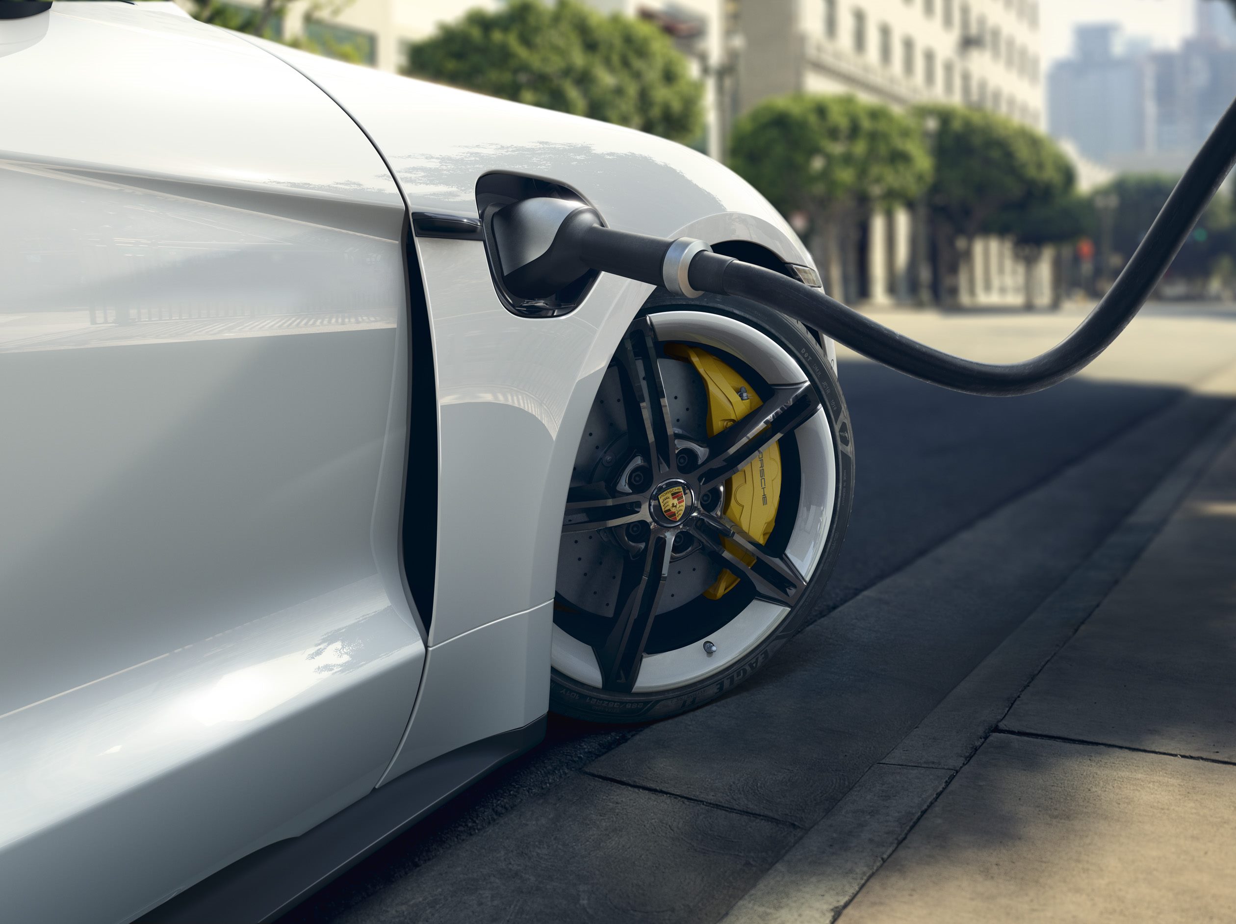 White Porsche Taycan charging cable and rim/yellow brake detail
